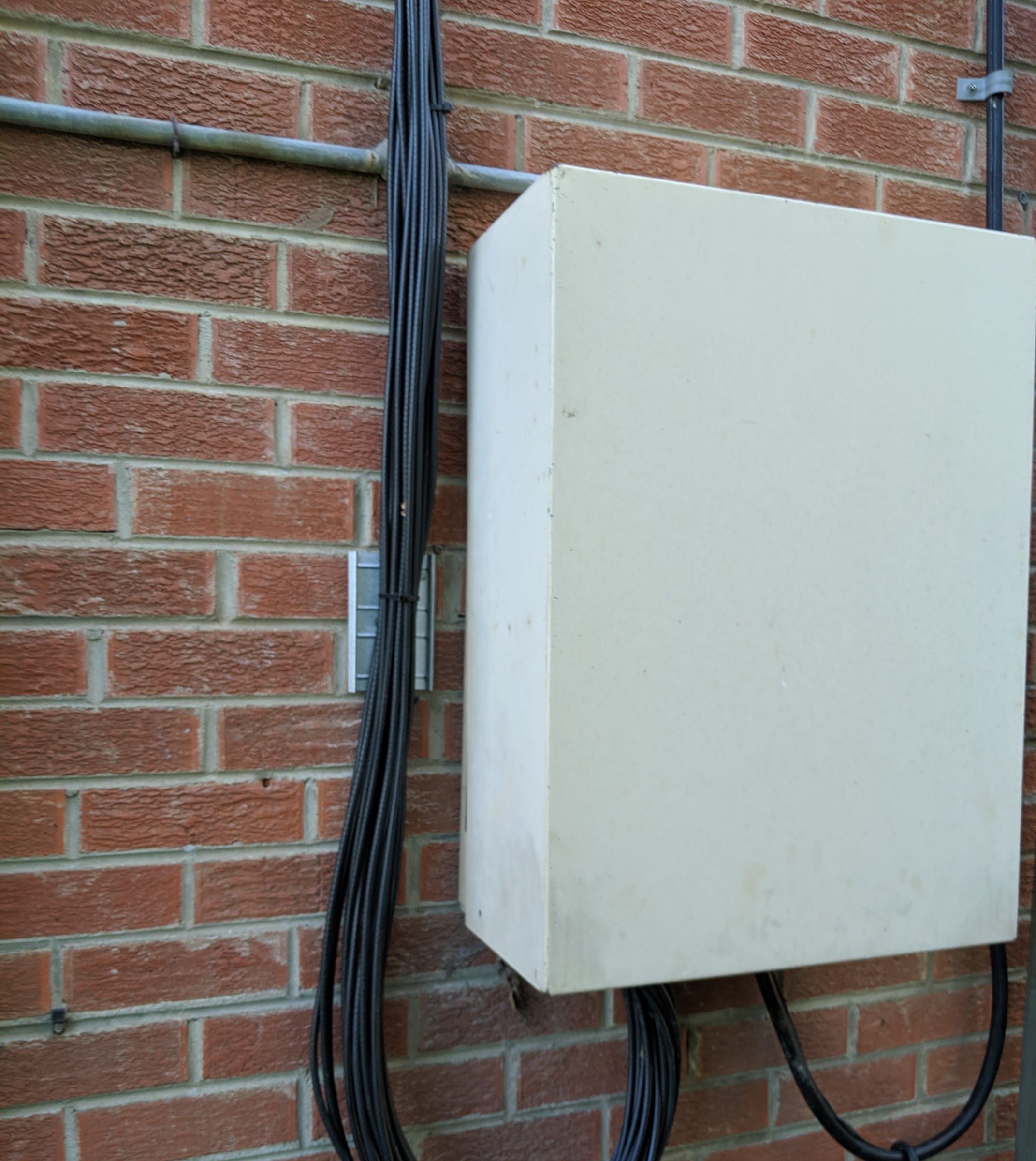 Exterior enclosure with looped cable on a brick wall