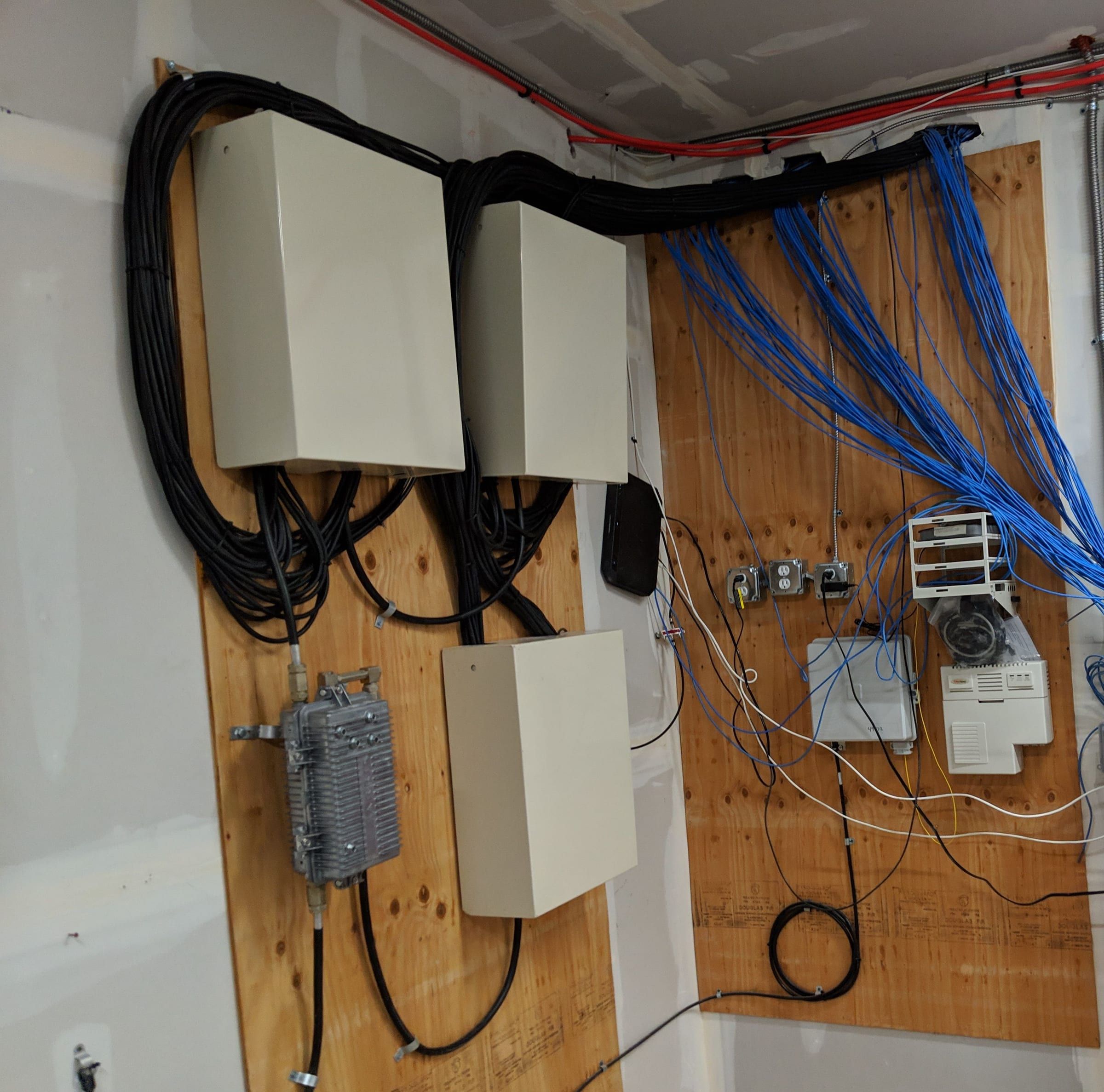 Cream enclosures with neatly looped black coax on a plywood backboard, blue cable runs beside them