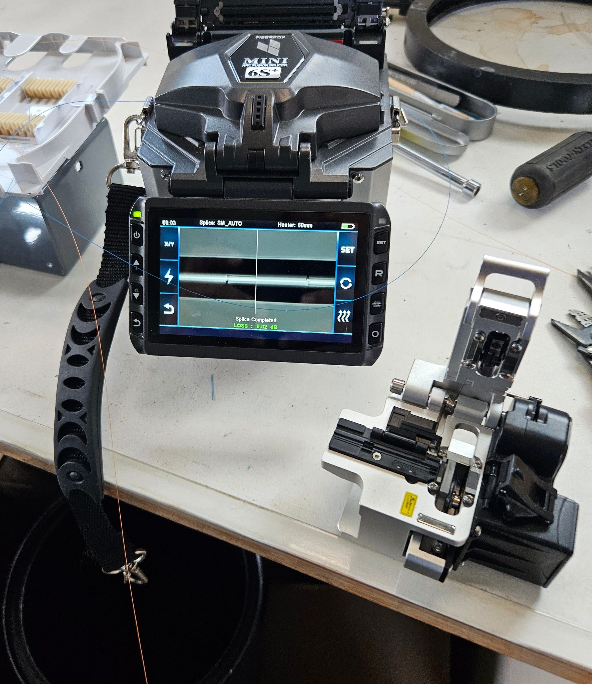 Fusion splicer showing a completed splice at 0.02 dB loss, cleaver beside it