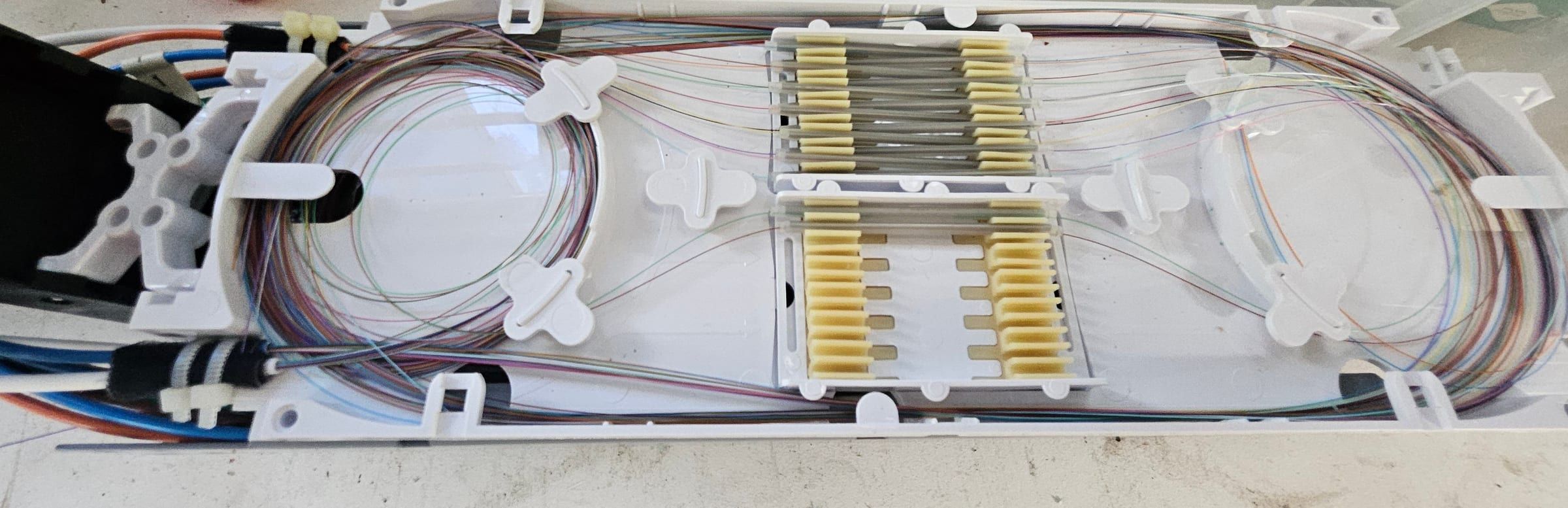 Open fiber splice tray with routed fibers and heat-shrink sleeves in their holders